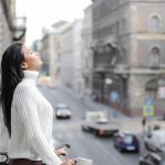 Woman enjoying a moment of relaxation on a balcony overlooking a city street.