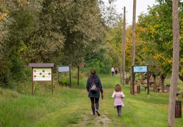 A parent and child walking on a path in a scenic nature reserve in Croatia, surrounded by lush greenery.